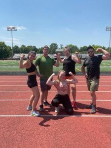 5 individuals flexing muscles on a running track