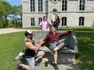 4 students pose next to an S.U. bench